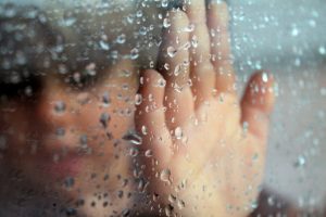 child looking through rainy window